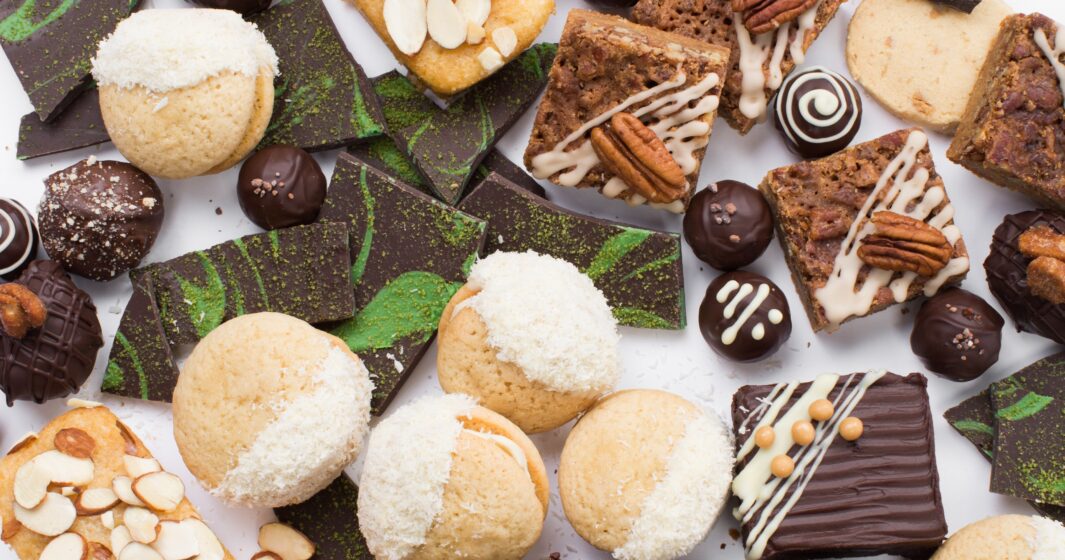 An assortment of cookies, brownies, and chocolate candies arranged on a white surface.